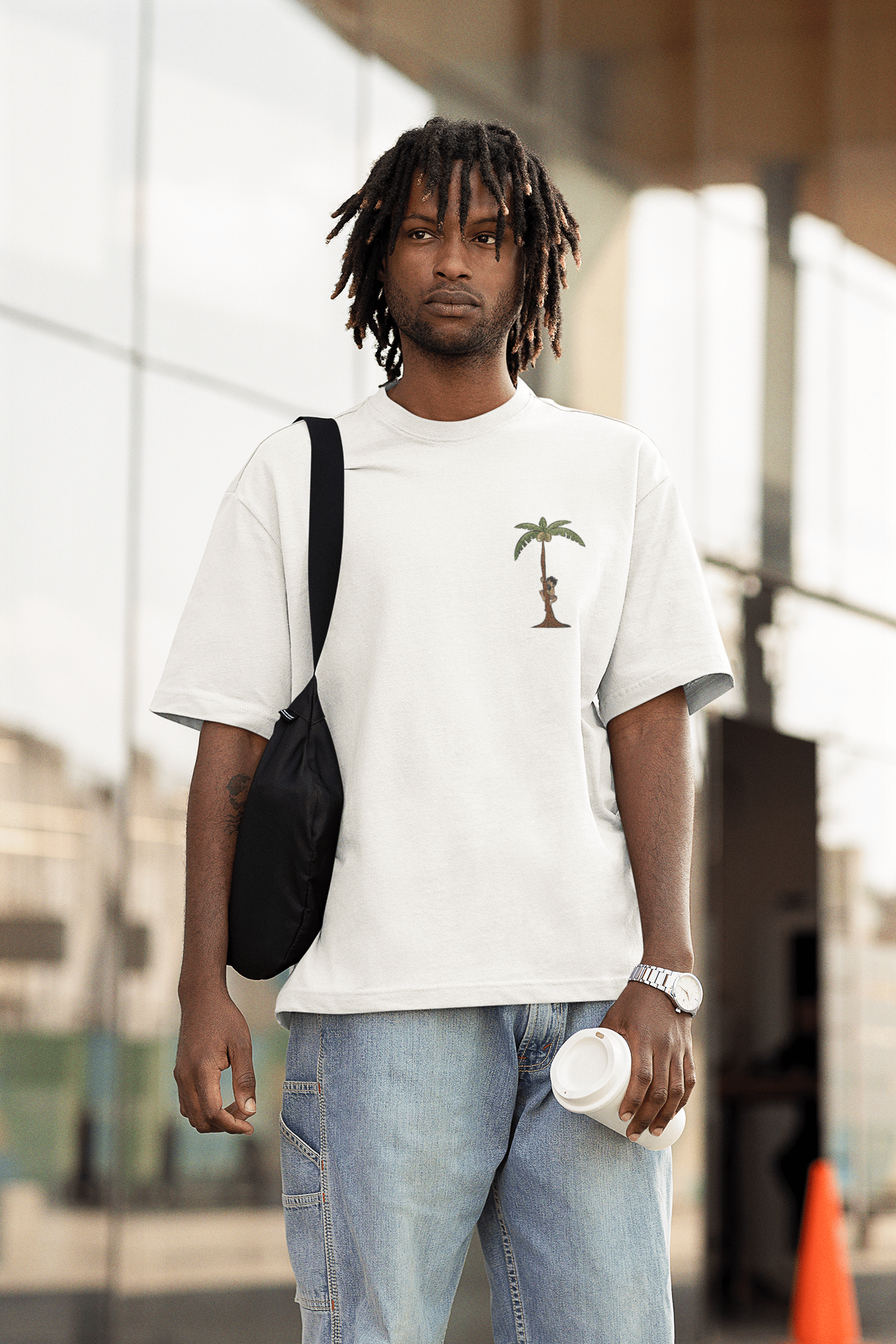 A model wearing white oversized tshirt with the illustration of man climbing a coconut tree indian streetwear, desi designs,